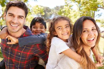 Young parents piggybacking their two kids outdoors