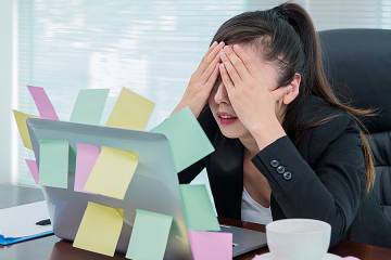Stressed woman looking at computer screen covered with sticky notes