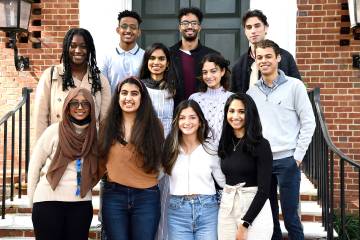 11 student volunteers pose for a photo on steps in front of brick home