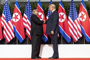 Trump and Kim shake hands in front of backdrop of U.S. and North Korean flags