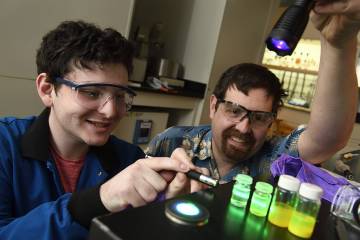 Tyrel McQueen (right) and a student observe how experimental materials respond to light
