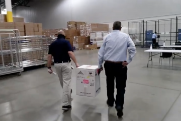 Two men carry a box between them