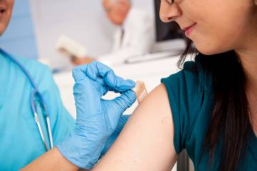 Nurse at pharmacy giving flu shot to young woman