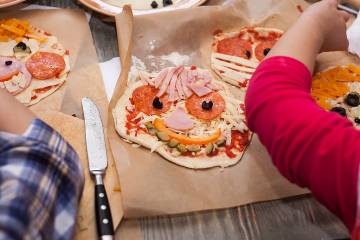 Kids making silly monster faces on pizza