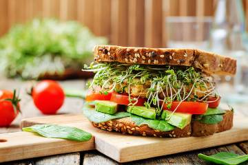 Sandwich of tomato, spinach, avocado, and chickpeas burger on whole grain bread