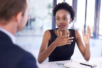 Woman at desk talking with colleague