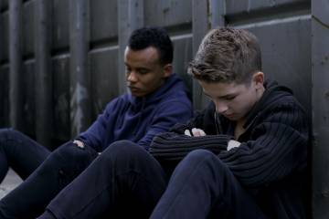 Two young men sit with their heads down