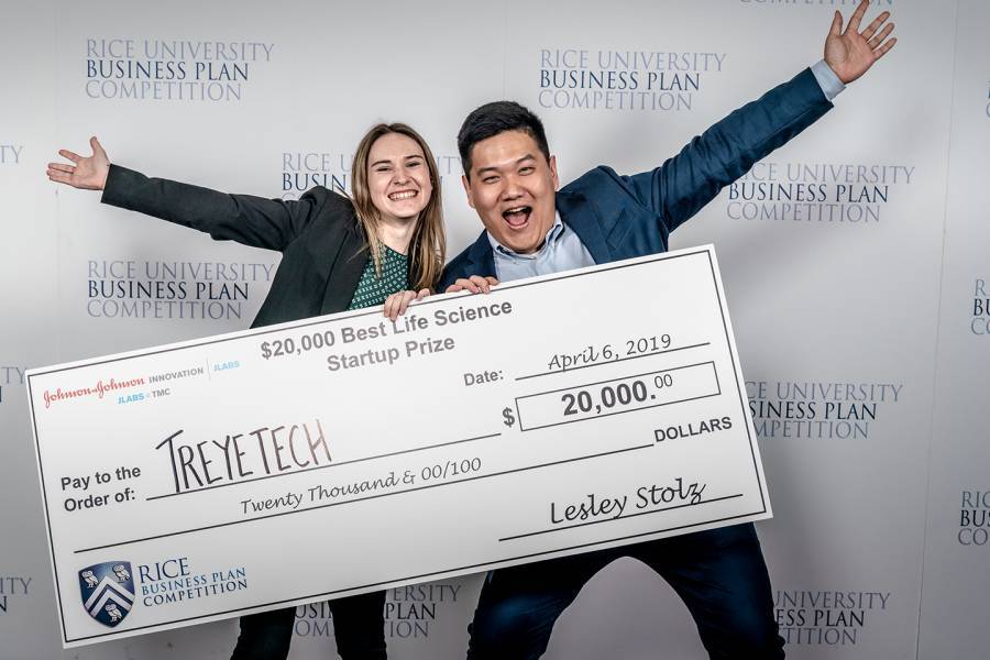 Two people hold a giant check