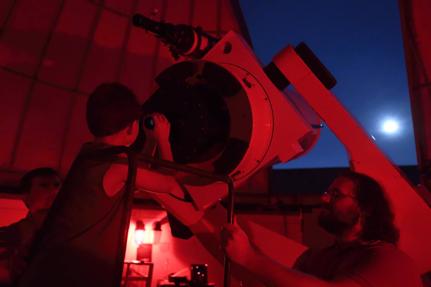 A child looks through a telescope at the moon