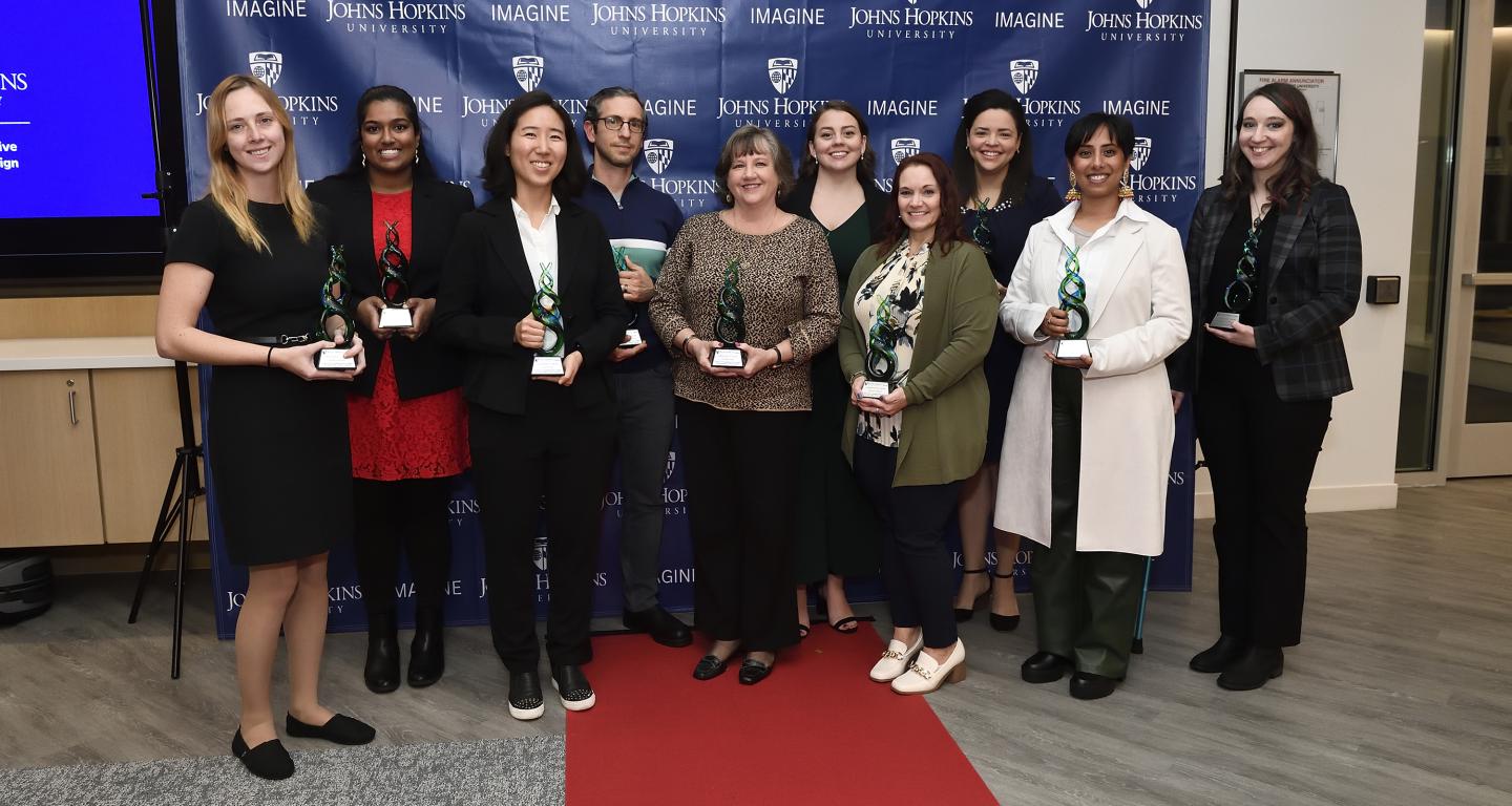 A group photo of 10 people holding awards