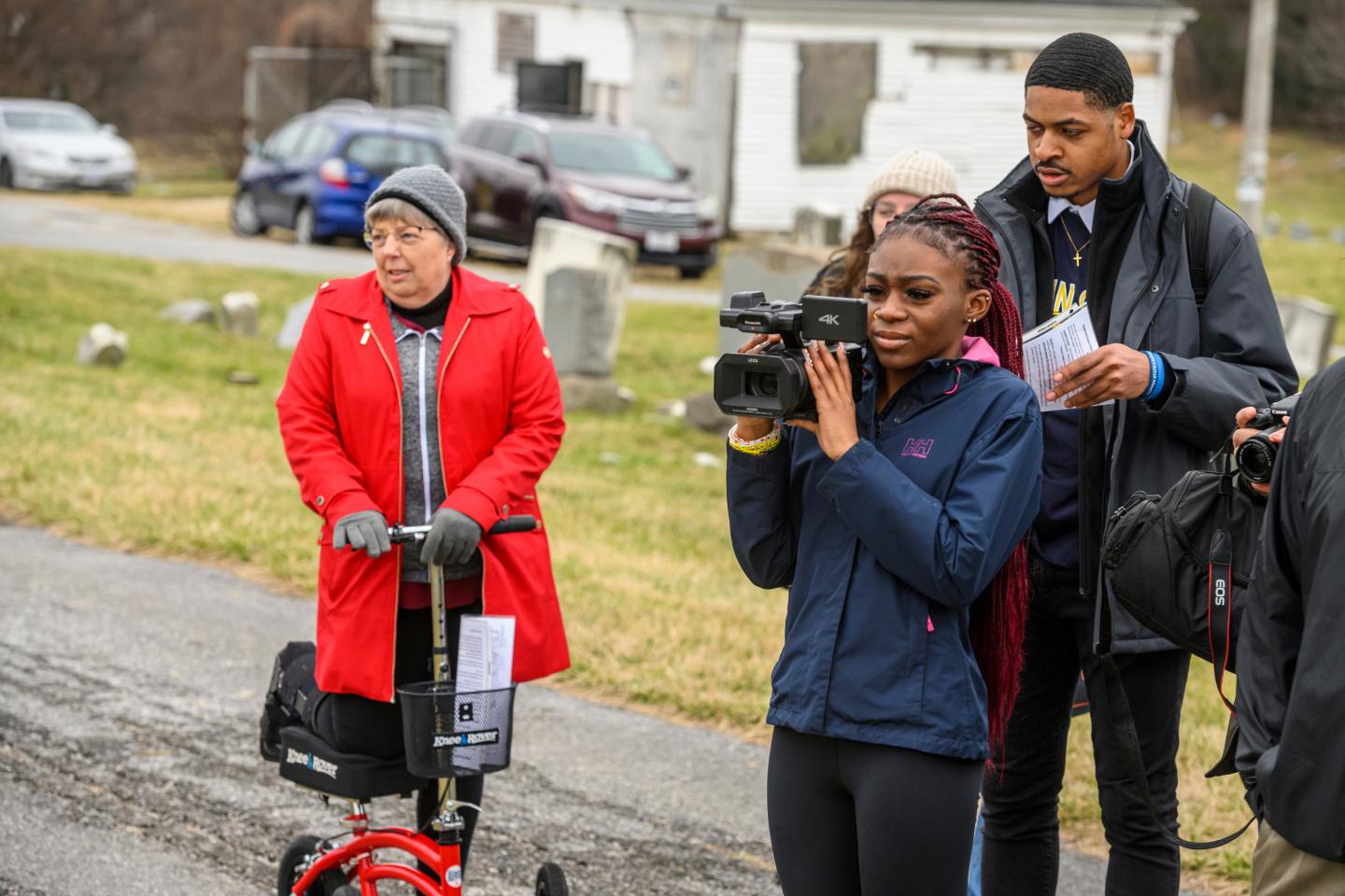 Students film a panoramic view of a cemetery