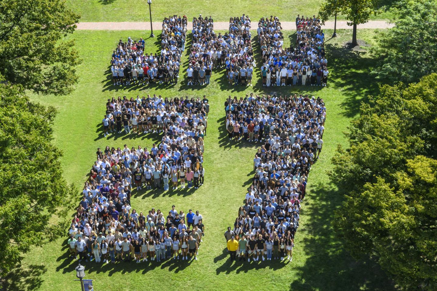 Hundreds of students, photographed from above, stand together to spell out 