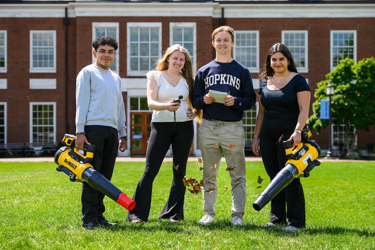 Four Johns Hopkins undergrads pose on the quad with their quieter leaf blower