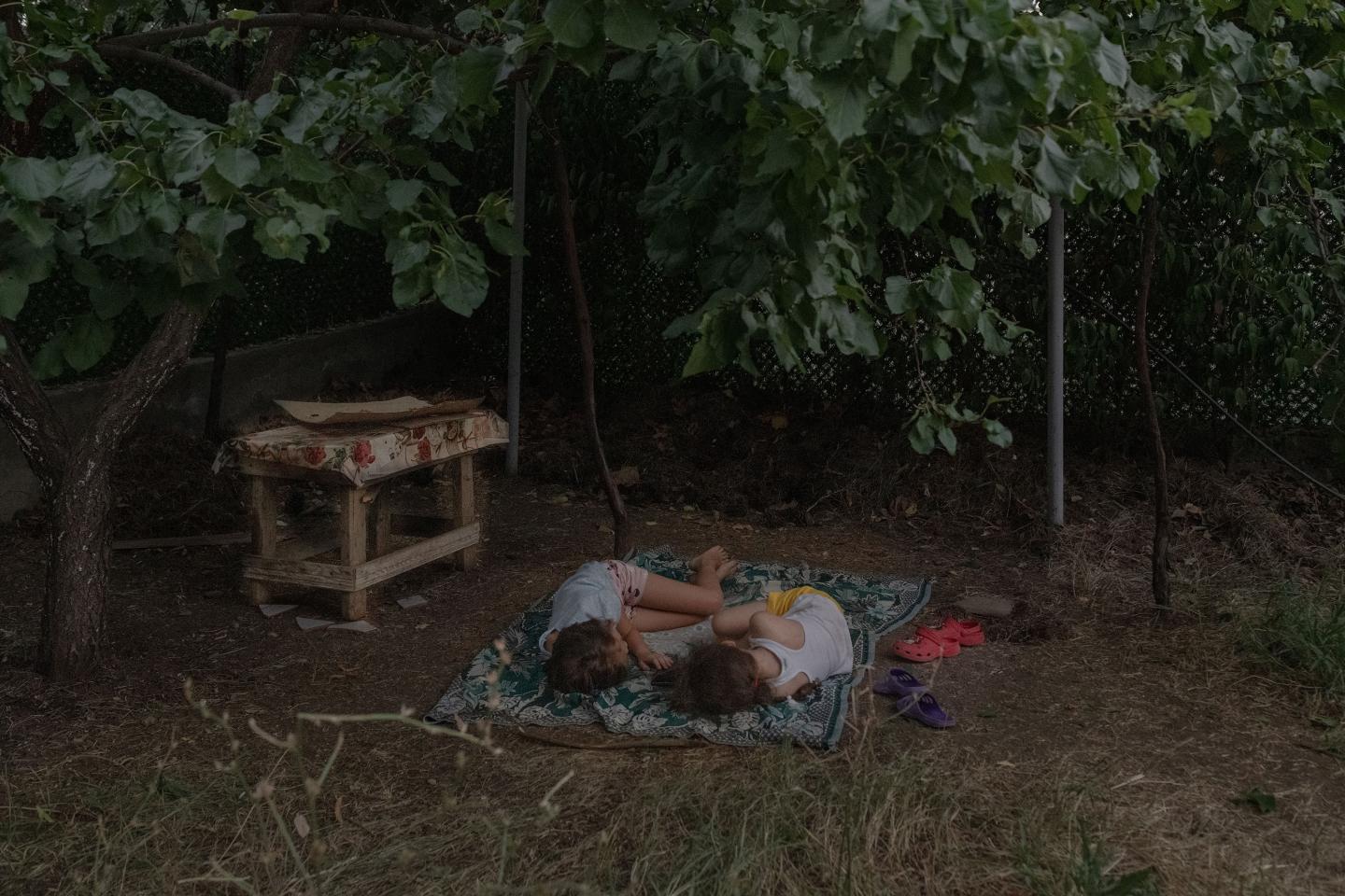 Two Ukrainian girls lay on a blanket while looking at one another 