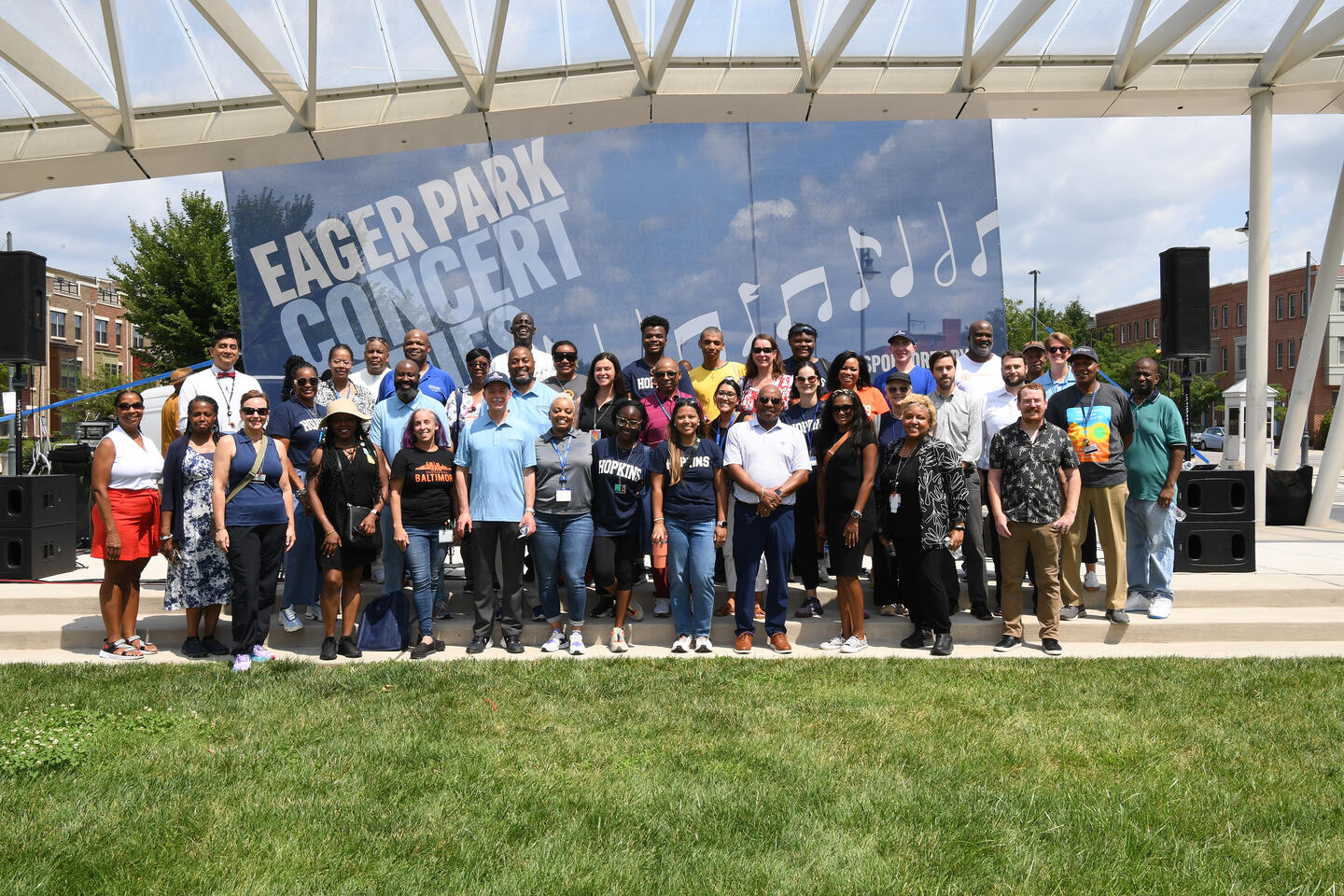 A group photo in front of the Eager Park Concert Series banner