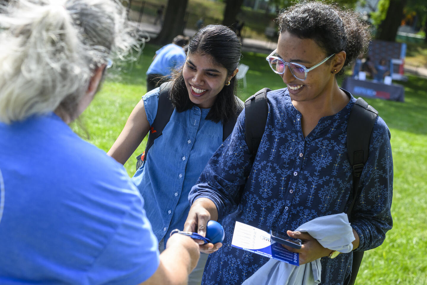 Two college students smile as they're offered a stress ball.