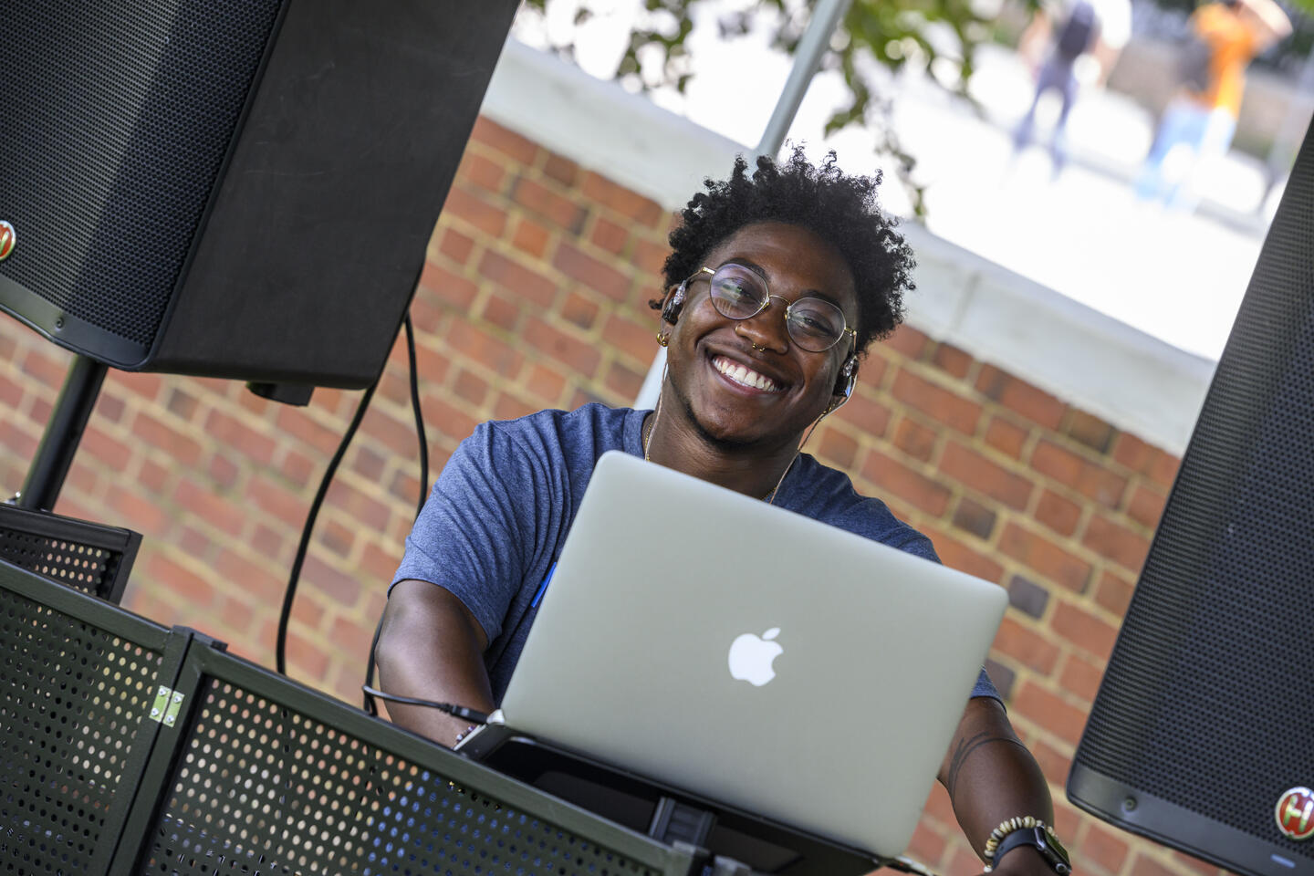 A DJ smiles from behind their laptop.