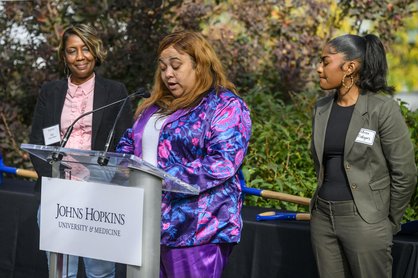 Three women stand a podium