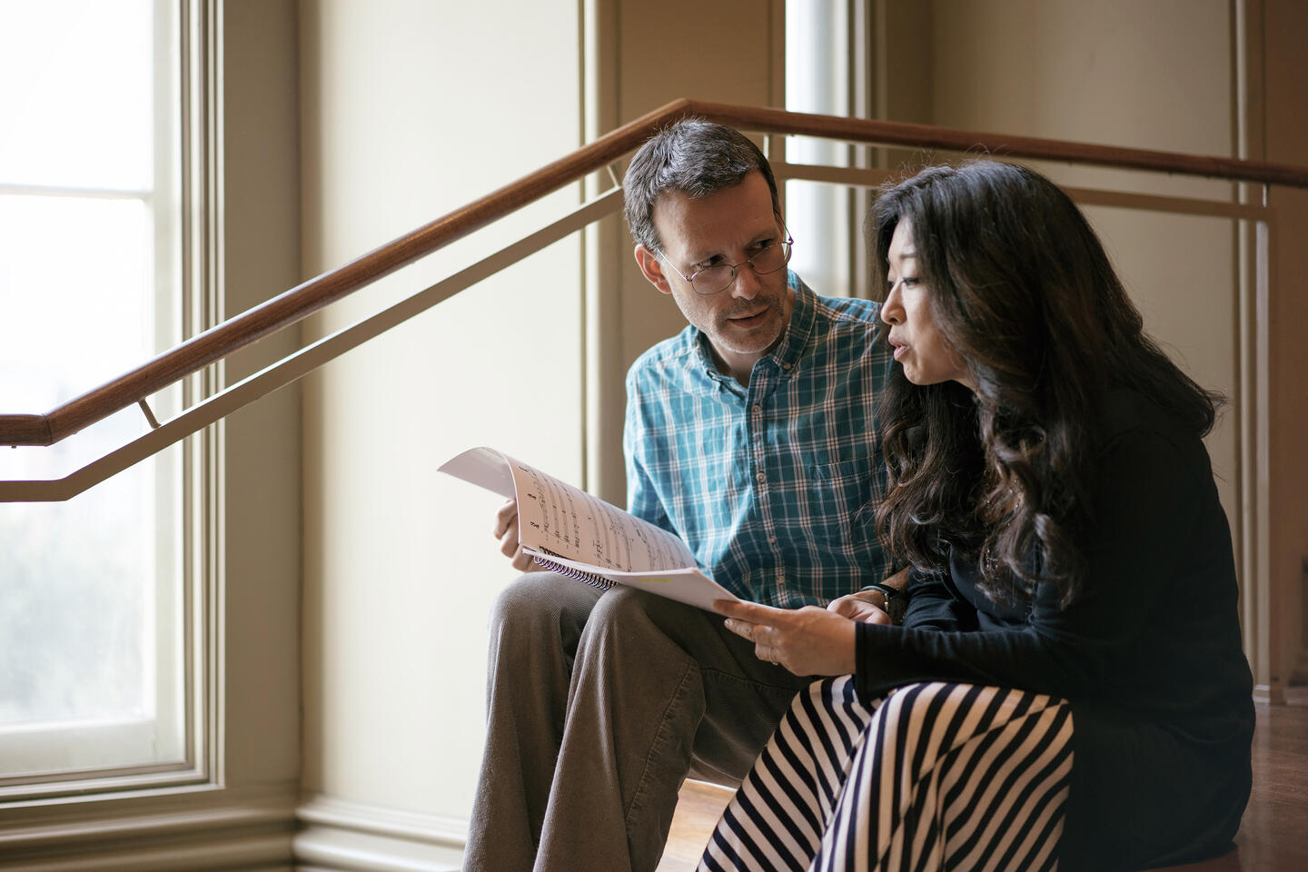 Two people sit next to each other in a stairwell