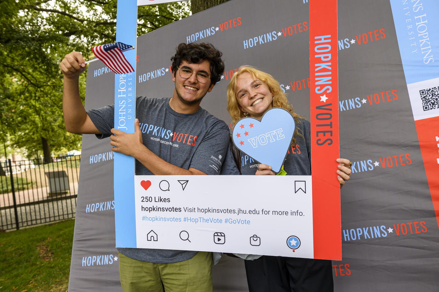 Two college students hold up a frame around their faces that looks like a Instagram post. The frame reads 