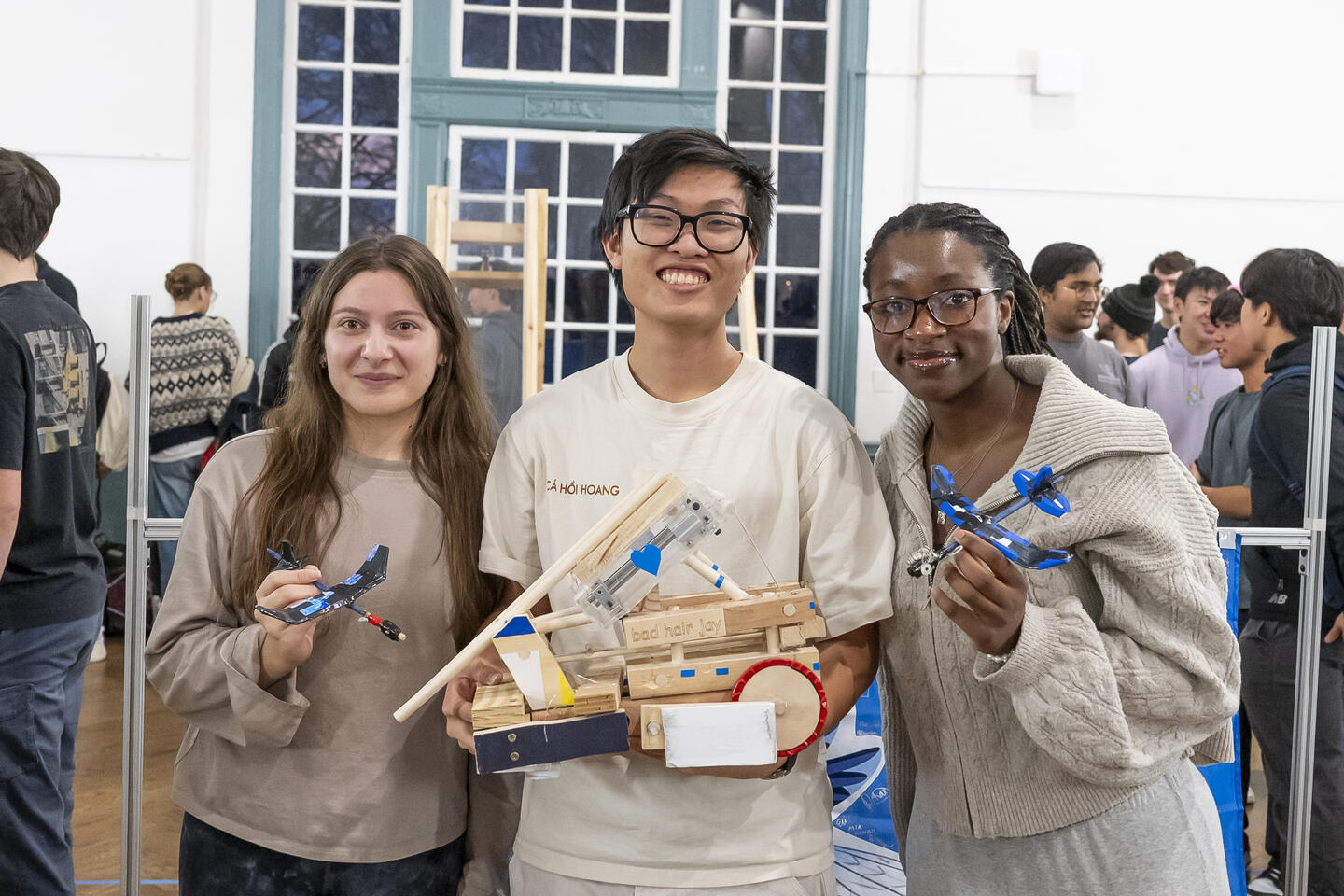 Three students on winning team Bad Hair Jay show off their victorious vehicles