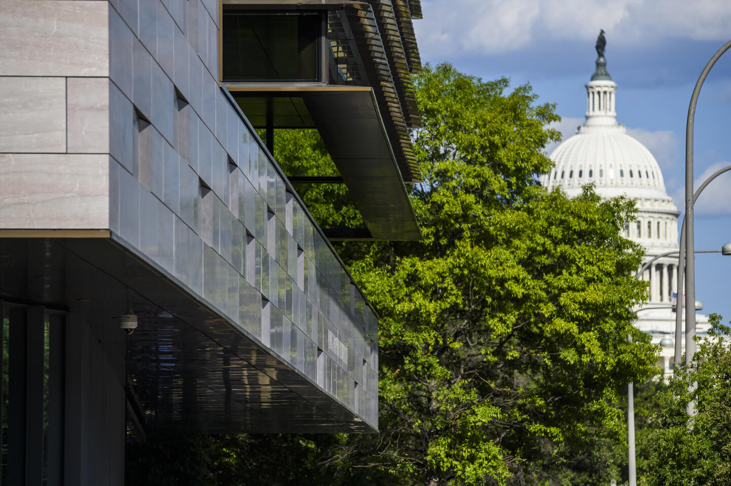 A close-up photo of the Johns Hopkins Bloomberg Center in DC. In the distance is the US Capitol building.