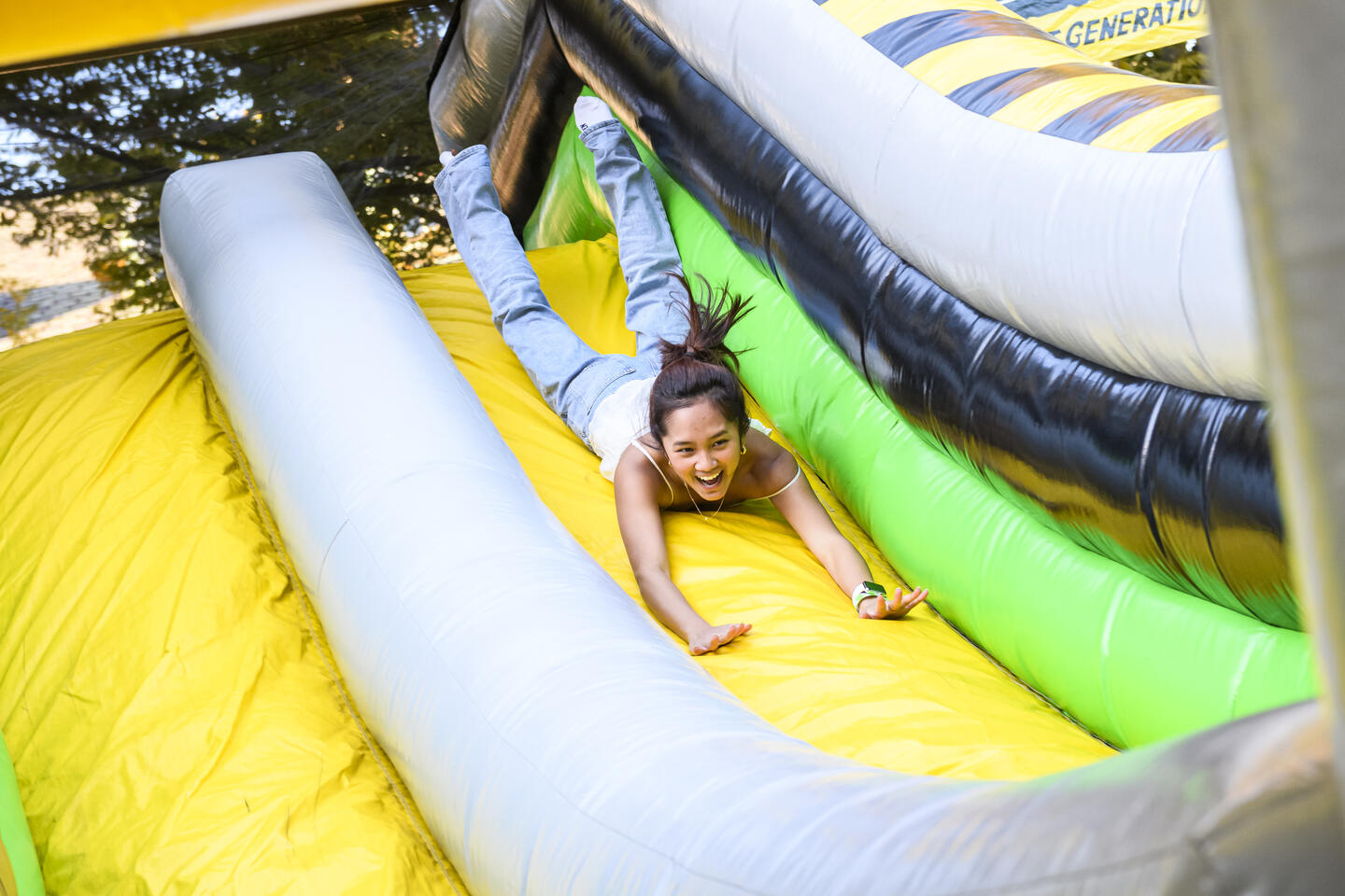 A young adult goes down a blow-up slide head-first.