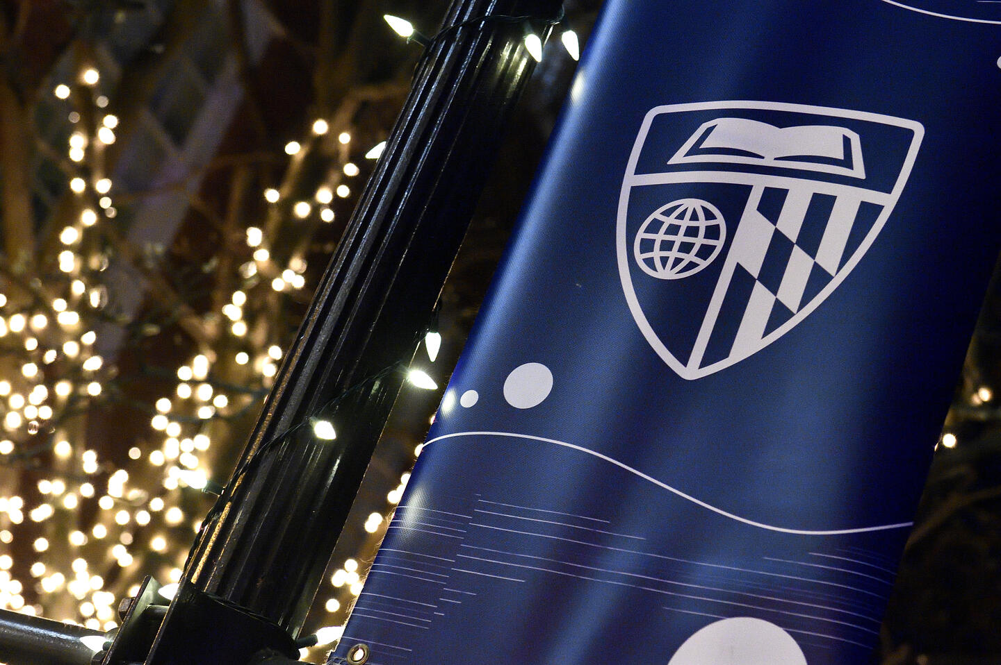 Holiday lights twinkle behind a banner with the Johns Hopkins logo.