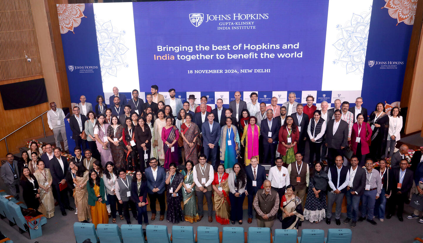 A large group of people stands and poses for a photo in an auditorium space