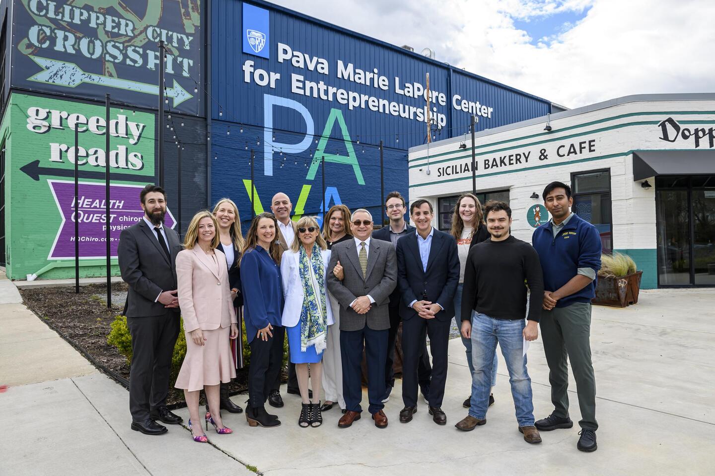 13 people stand for a group photo in front of the Pava Marie LaPere Center for Entrepreneurship.