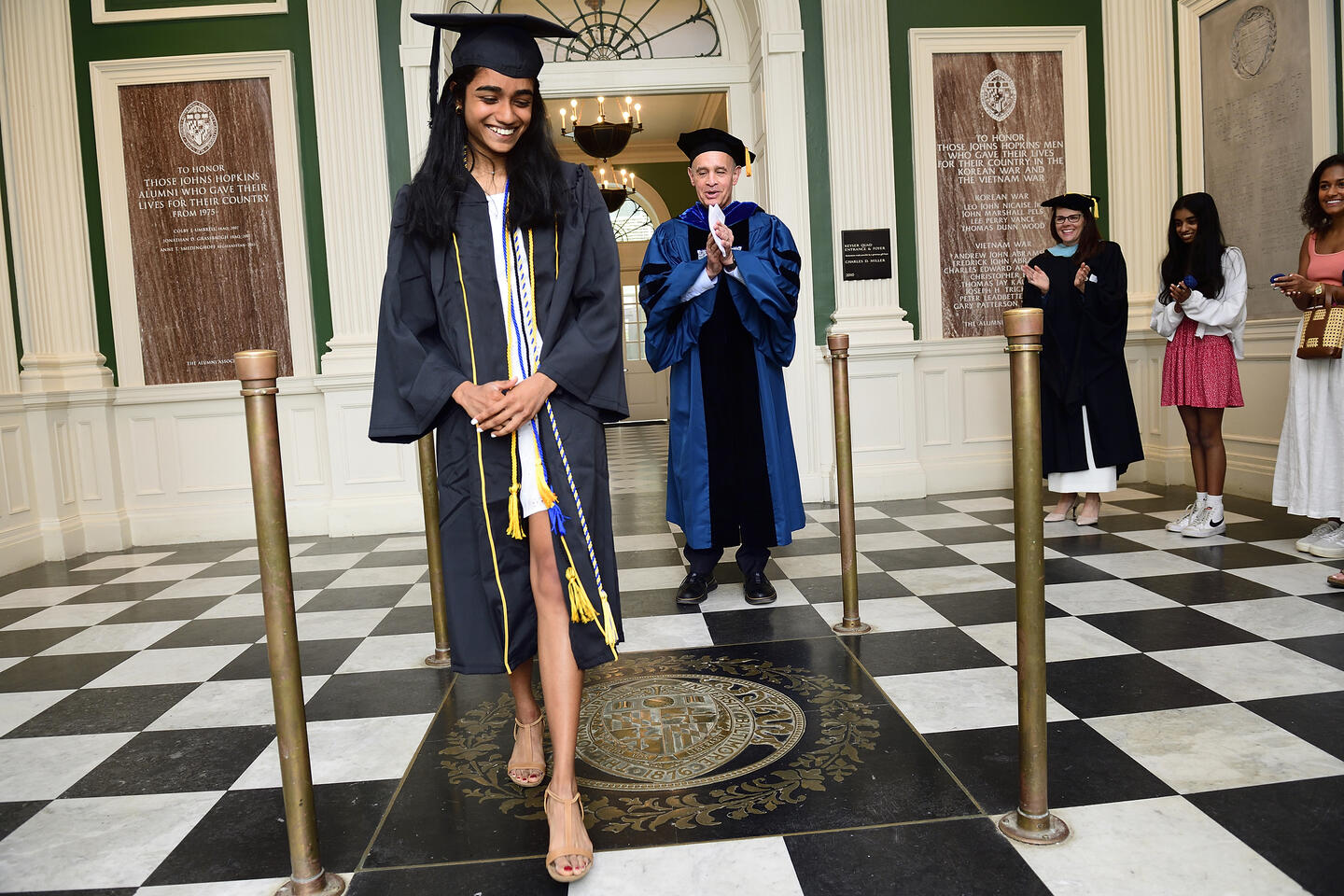 Harrinee Senthilkumar steps on the JHU seal in Gilman Hall after receiving her degree