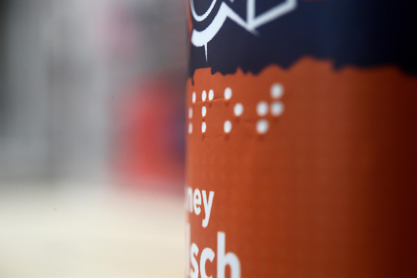 A closeup on an orange and dark blue label on a beer bottle featuring Braille text
