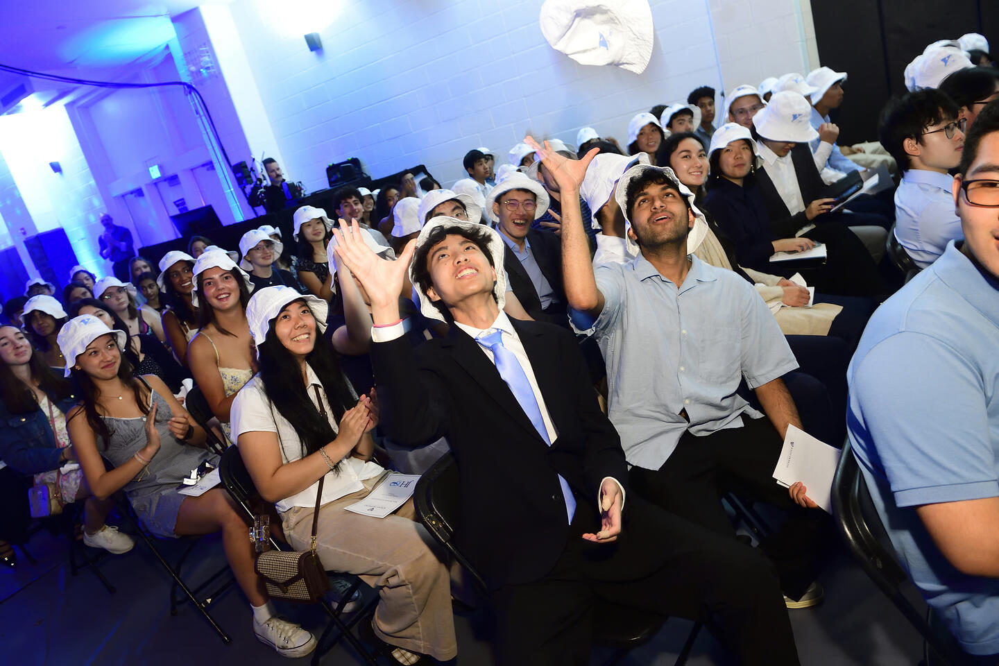 Students tossing their bucket hats in the air in celebration