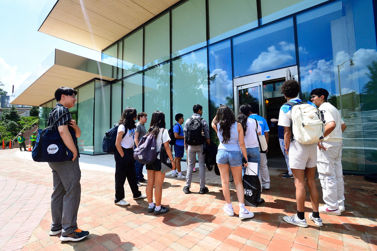 A group of about 12 students congregate outside an entrance to a news building