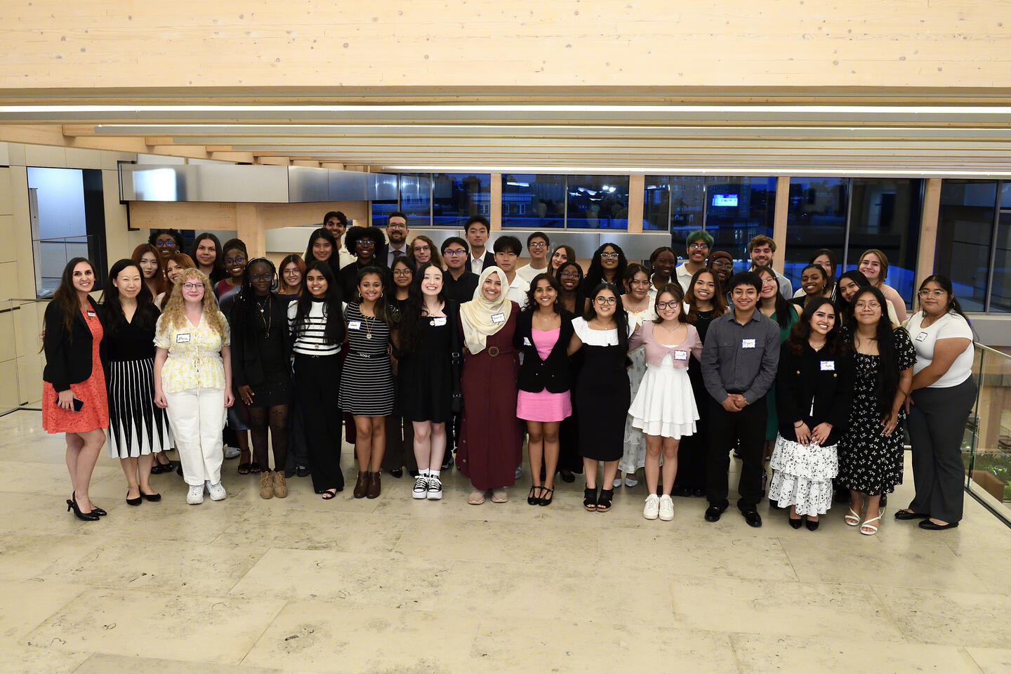 A large group photo of several dozen college students in formal outfits.