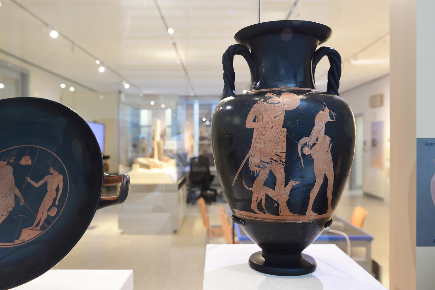 A black urn with dark orange figures on it 