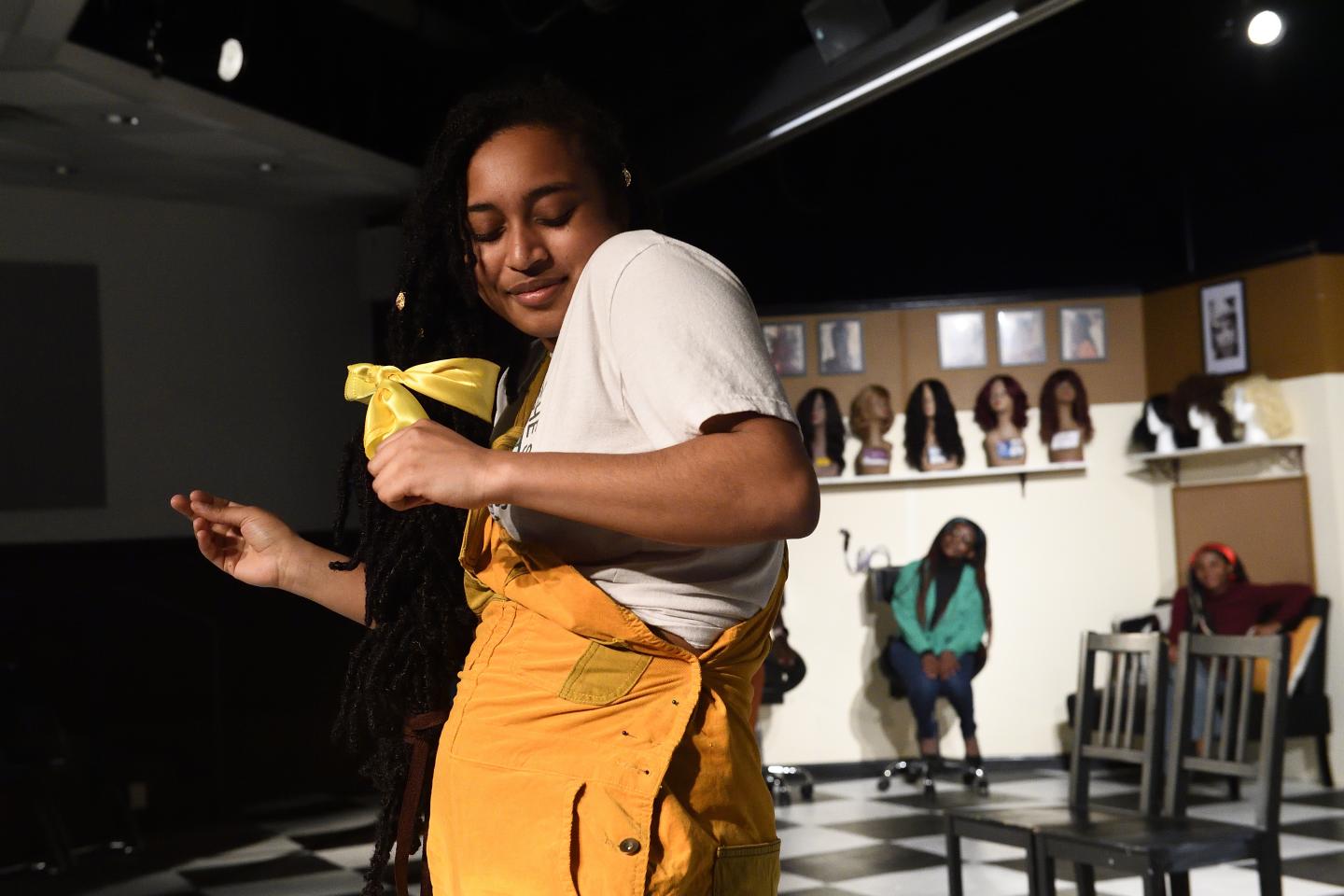 An actor dances on stage while other players watch.