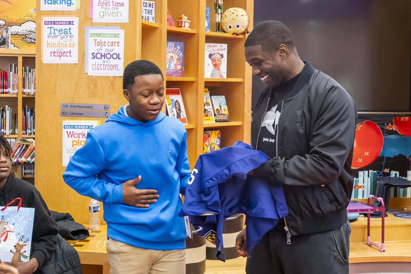 A student smiles while Roquan Smith signs a jersey for him