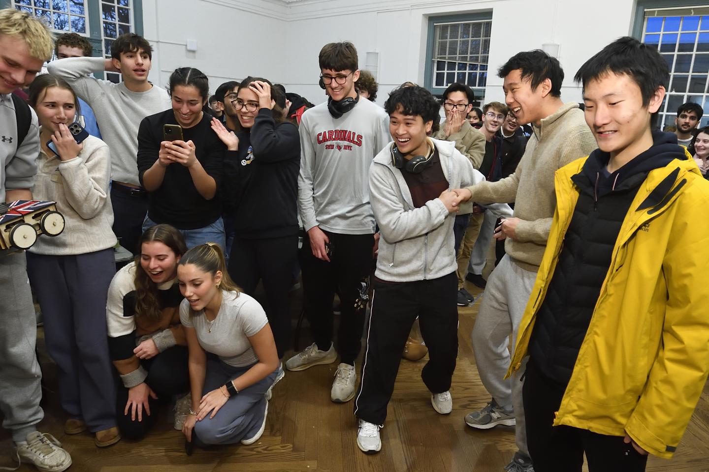 A group of college students have mixed reactions to something out of frame.