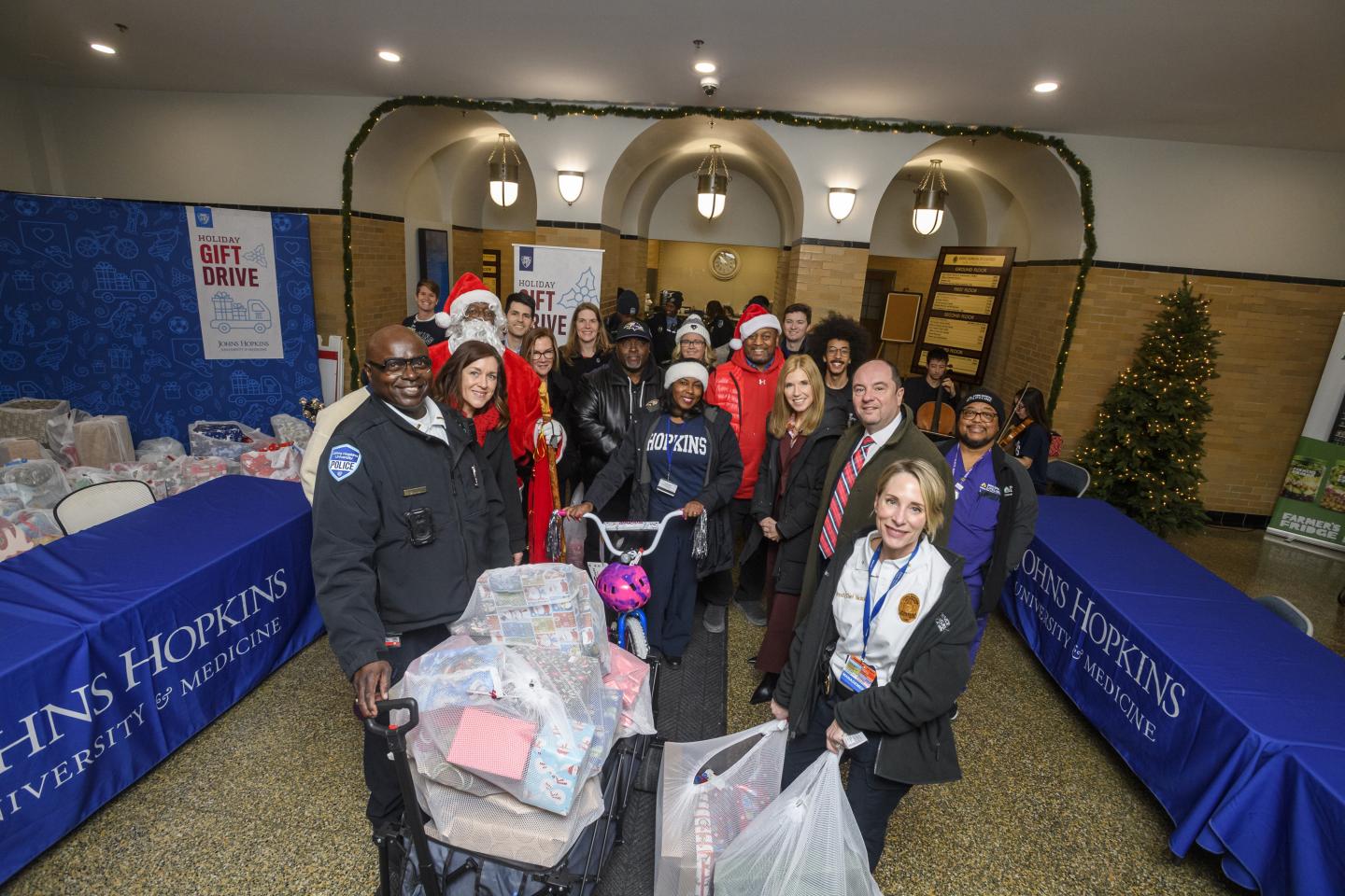 Johns Hopkins affilates pose in the lobby of JH at Eastern with gifts for the holiday drive