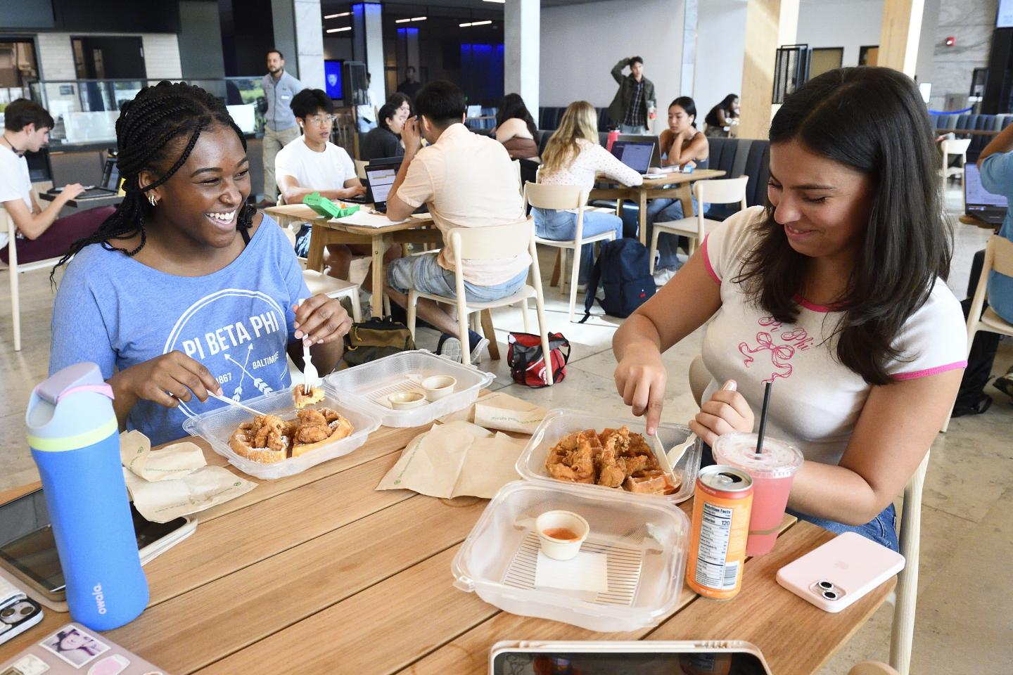 Two college students eat lunch in the Bloomberg Student Center's food hall.