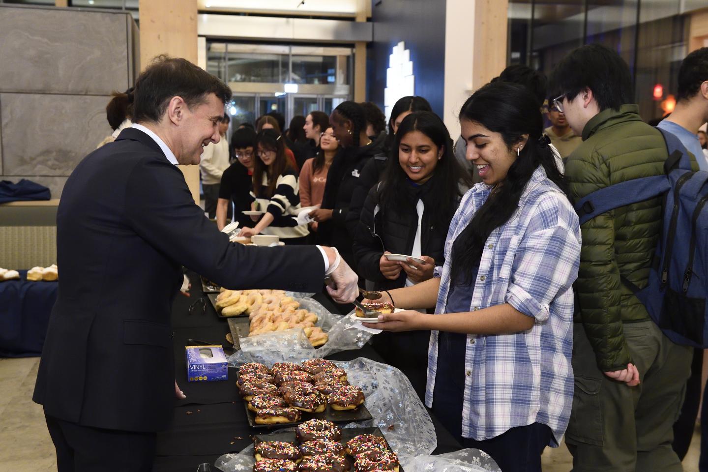 Ron Daniels serves pastries to a line of students in the Bloomberg Student Center.