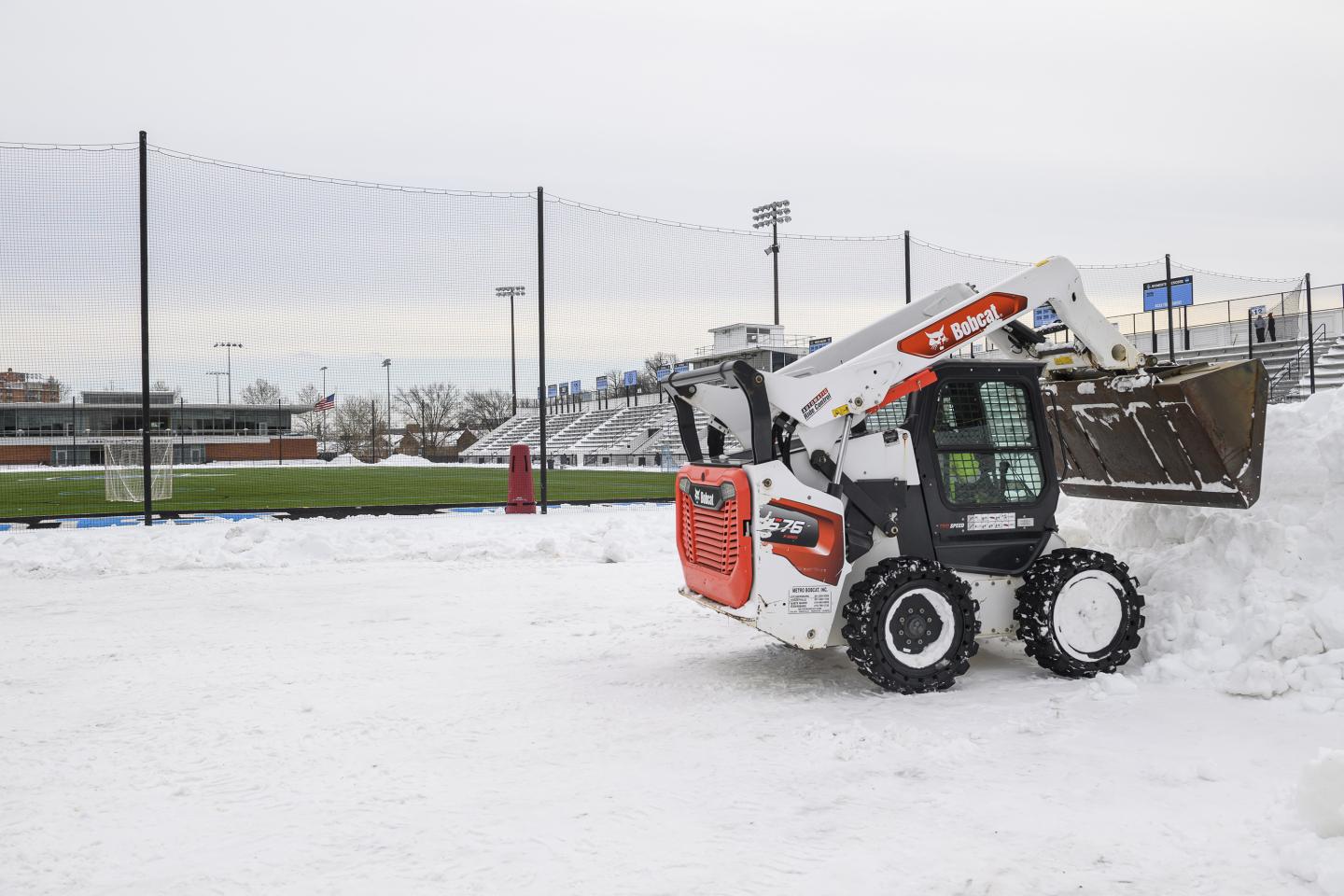 A piece of snow removal equipment clears snow from Homewood Field