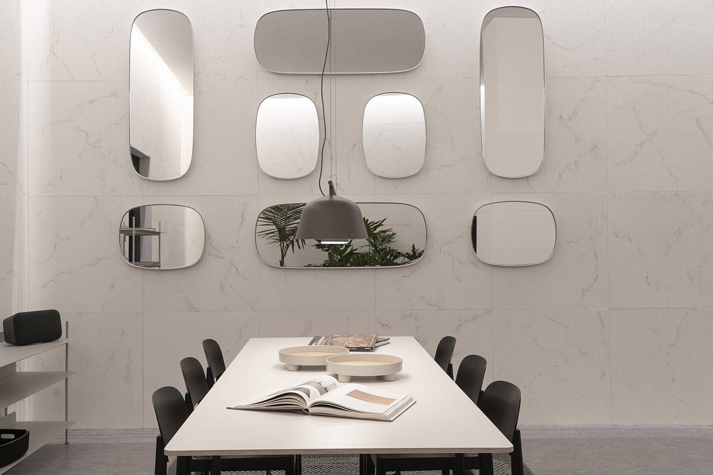 A dining room with natural marble walls, round mirrors, and sleek furniture
