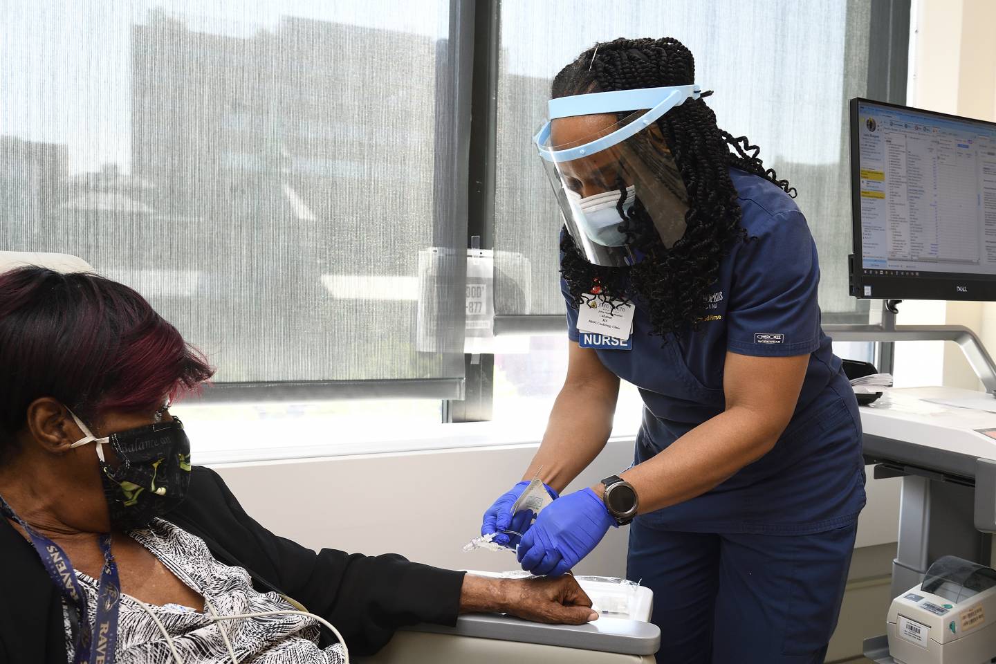 A nurse inserts an IV into a patient's hand