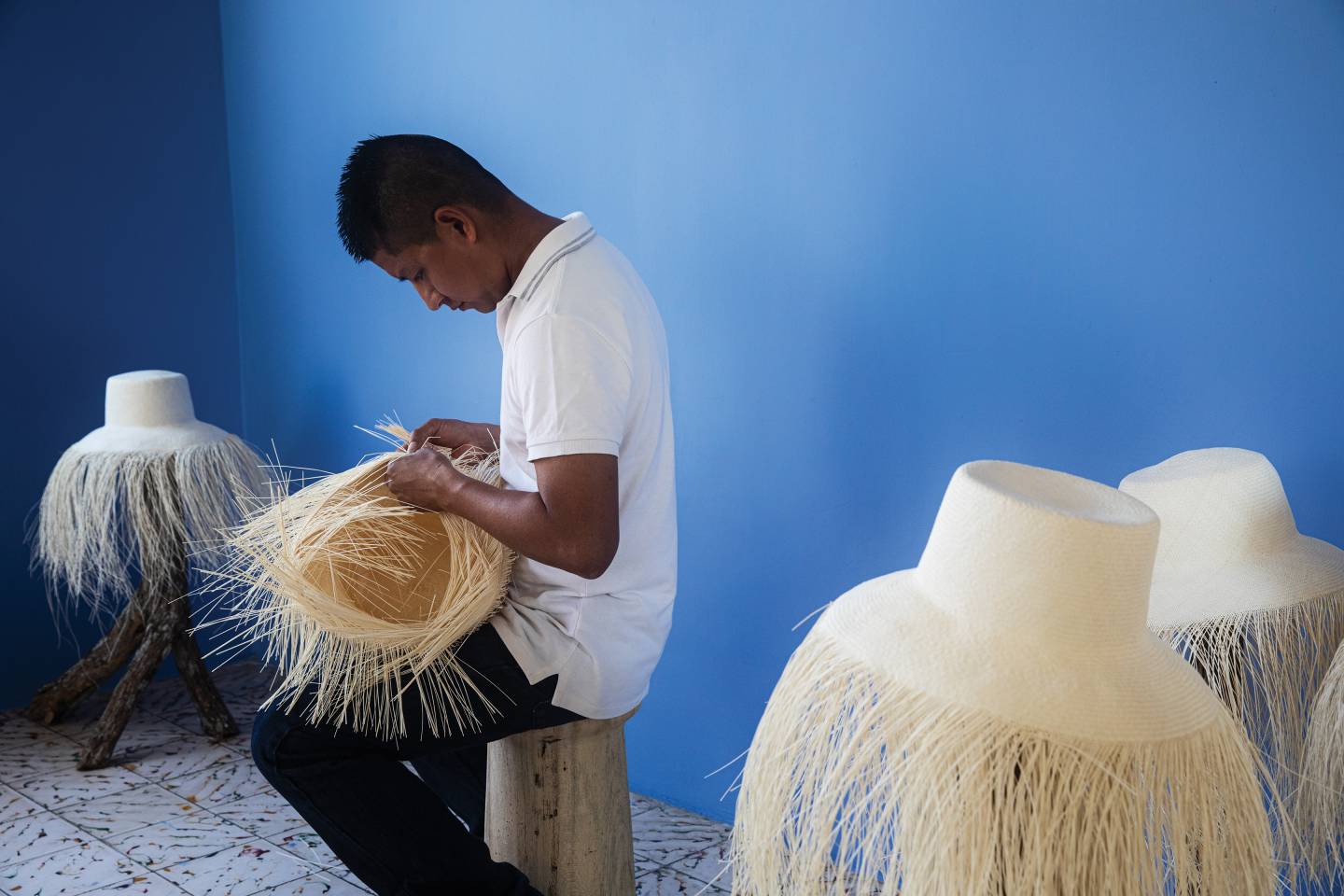 An artisan weaves a Panama hat in a workshop