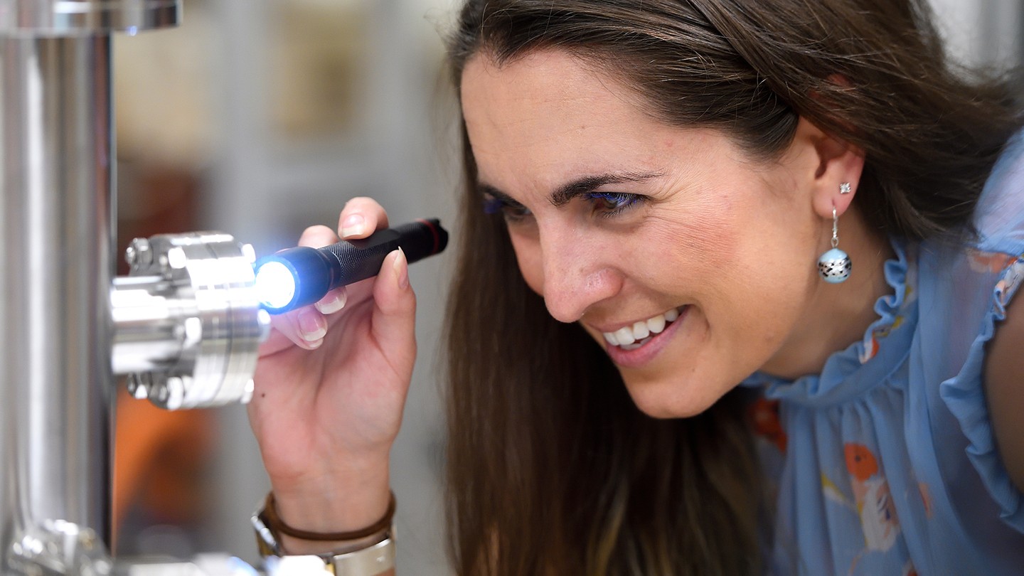 A woman uses a flashlight and what looks like a microscope