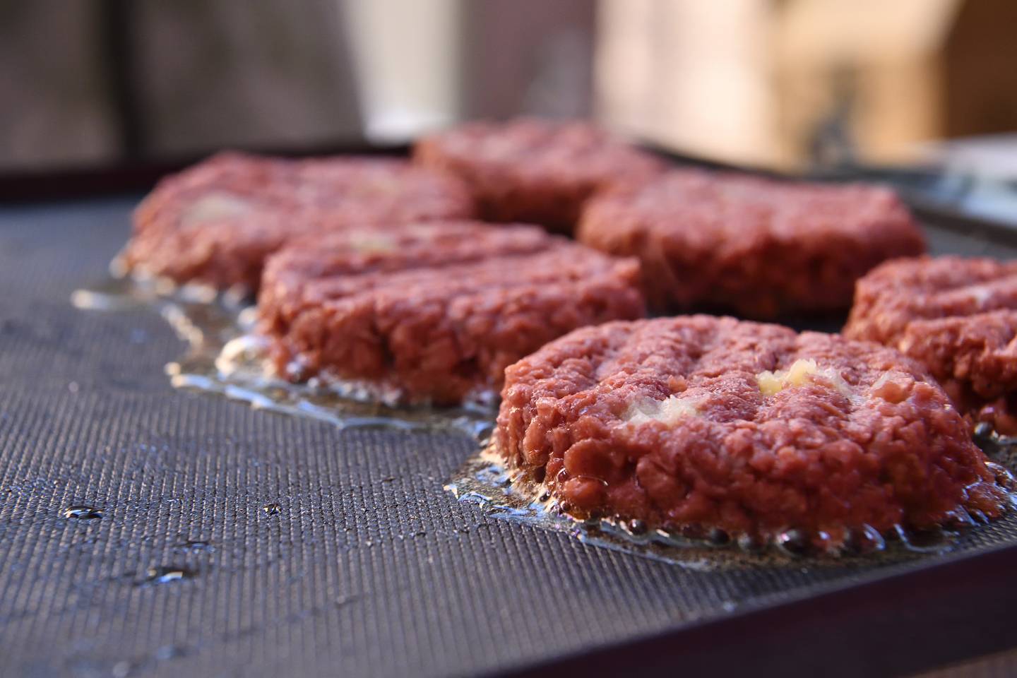 Meatless burgers cook on a griddle