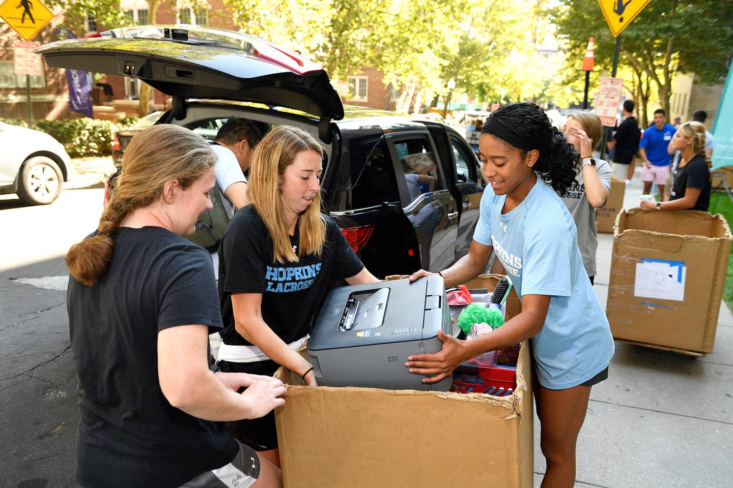 Students load rolling bins with luggage Students load rolling bins with luggage