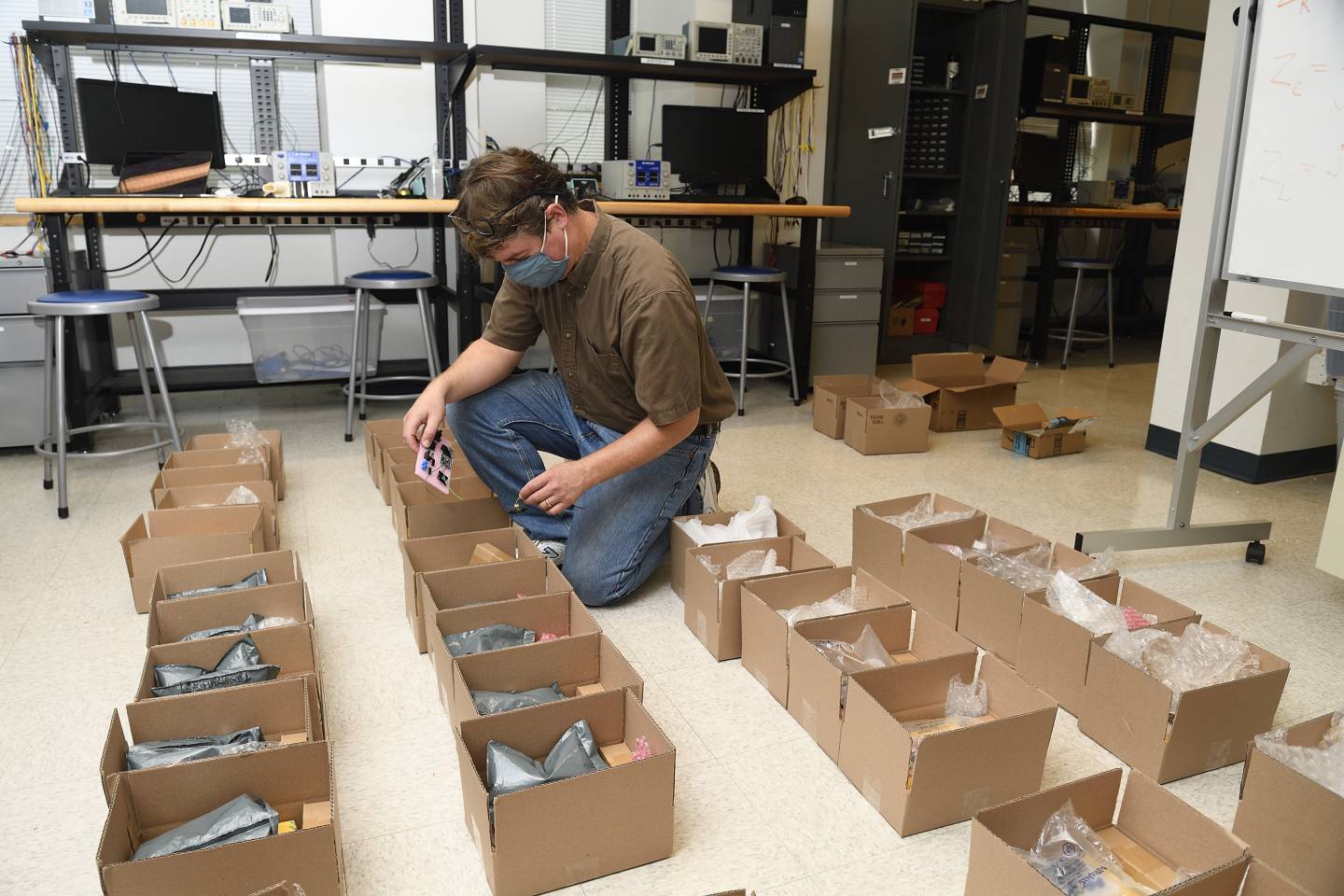 A man kneels beside open boxes